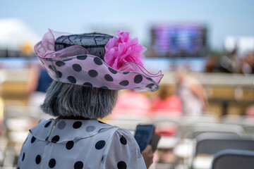 An attendee at a horse race, wearing a fancy hat.