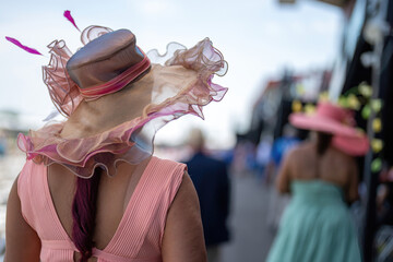 An attendee at a horse race, wearing a fancy hat.