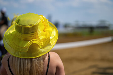 An attendee at a horse race, wearing a fancy hat.