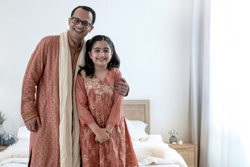 Loving Indian daddy and little adorable daughter hugging and looking at camera in bedroom at home,...
