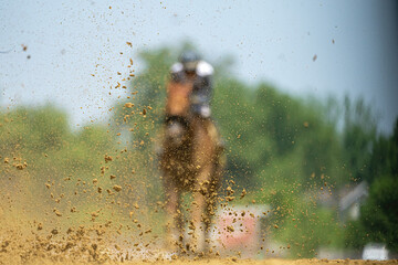 Dirt is kicked up as a horse runs past on a race track.