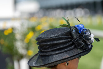 An attendee at a horse race, wearing a fancy hat.