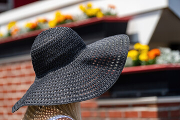 An attendee at a horse race, wearing a fancy hat.