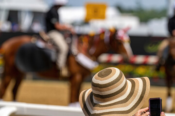 An attendee at a horse race, wearing a fancy hat.