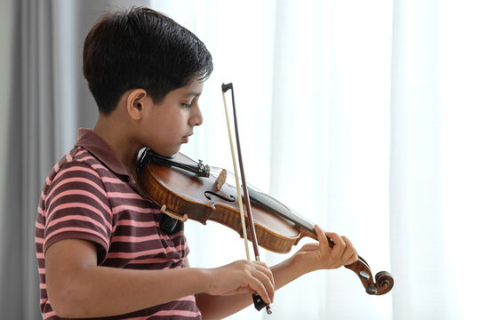 Indian boy practicing violin at home playing the violin by the window at home