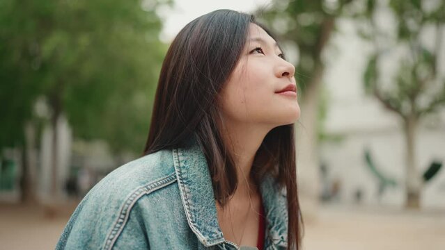 Beautiful long haired Asian woman looking inspired taking photos of beautiful city on smartphone