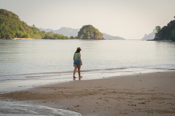Young Caucasian Girl wearing summer clothes walking on the beach. Langkawi, Malaysia
