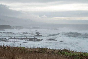 rocky cliff with fog and ocean waves