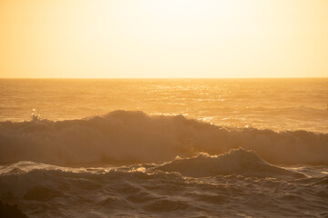 warm sunset over crashing ocean waves