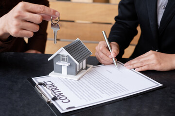 A real estate agent broker hand over the house key to the new owner after completing the signing...