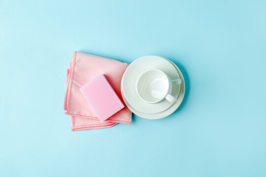 Set of pink sponges and white cups on blue background, kitchenware, house cleaning service concept, copy space, banner, flyer, mockup, minimal design