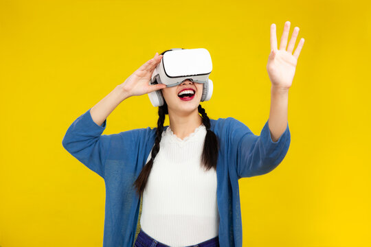 Metaverse Concepts, Asian woman in vr glasses isolated yellow background, playing video games with virtual reality headset, People emotions concept.