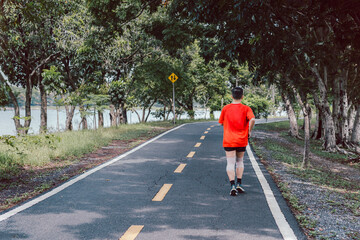 Back view of asian man jogging in park in summer.
