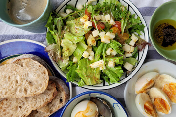 Toasted bread, boiled eggs, olive oil salad bowl. Daily healthy breakfast. Top view image.