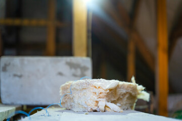 A close-up of a piece of yellow glass wool lies on a table in the backlight. Universal insulation...