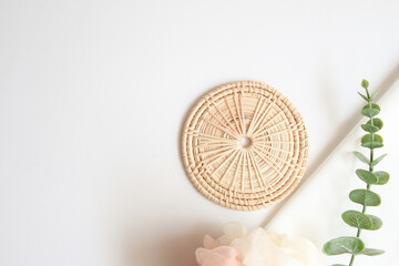 rattan coaster and white fabric background for cosmetic products. top view, copy space.