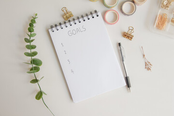 Text list goals on notebook with pen on white background, office desk.
