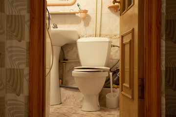 Bathroom, toilet bowl in the toilet in a residential apartment with an open door to the bathroom, toilet