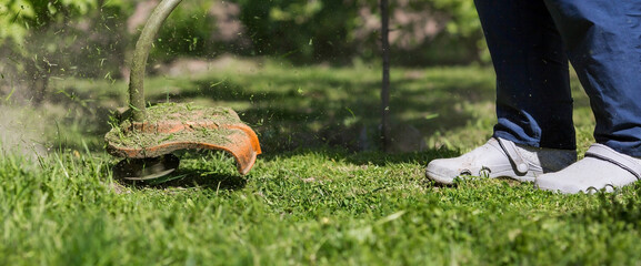 Banner. A human lawn mower cuts the grass in the backyard. Agricultural machinery for the care of the garden.