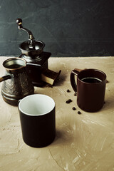 coffee grinder two mugs of cinnamon coffee beans and a turk for brewing coffee on the table