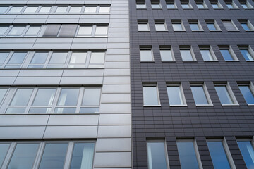 Two office buildings together with a light and dark gray facade and many windows