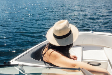 woman in straw sun hat sitting in bow of recreational motorboat looking out at water