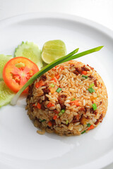 Above view of Asian fried rice with egg and vegetable in white ceramic plate on the table in the restaurant. Khao Pad popular traditional Thai style food. Top-down