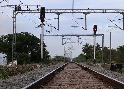 Railway tracks with electrification and red signals near Tanjore, India.