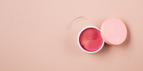  Pink hydrogel eye patches in a box with an open lid. Banner with cosmetology concept and place for text.