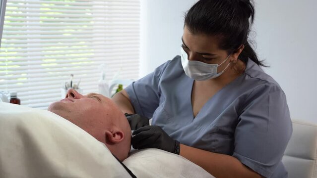 Cosmetologist making injection in man head for hair growth, beauty injections in the back of the head of male patient for hair growth and to prevent baldness. mesotherapy session in a salon