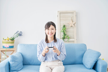Obraz premium リビングで笑顔でテレビゲームをする女性