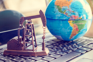 Petroleum, petrodollar and crude oil price concept : Oil rig or a pumpjack on a laptop, depicts the direct impact of global sanctions on oil exporting countries on online oil ordering over internet. - obrazy, fototapety, plakaty