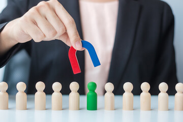 Business woman hand holding magnet and pulling man wooden figure from the crowd employee. Business, Human resource management, Recruitment, Teamwork, strategy, toxic people and leadership Concepts