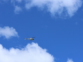Helicopter on a background of blue sky and white clouds