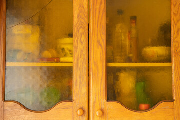Old brown wooden kitchen cabinet with glass doors in the kitchen at home, kitchen furniture