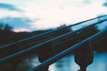 Carp fishing rods and bite alarms in moody evening light. Abstract close up with shallow depth of field.