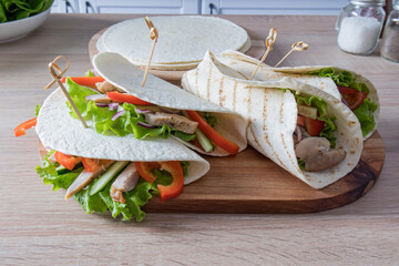 freshly made homemade tortillas or buritto on a wooden board for serving food. filling of ripe vegetables and chicken fillet. vegetarian food.