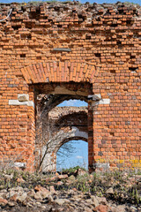 A ruined ancient Christian church made of red brick in summer in the daytime against a blue sky