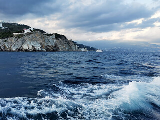 beautiful landscape where on the horizon behind the black sea with waves you can see the Crimean city in the mountains