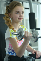 Beautiful teen girl is exercising in the gym