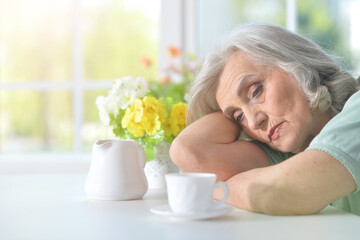 sad senior woman drinking tea at home