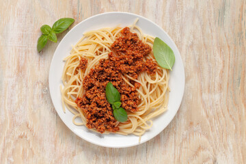 Pasta Spaghetti Bolognese in white plate on wooden background. Bolognese sauce is classic italian cuisine dish. Popular italian food. Top view