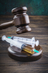 Wooden gavel and medical syringes. Legal cases of medical negligence or a sentence for drug distribution concept - 506567748