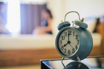 Soft light and Blurred image, alarm clock placed next to bed woke up at set time for woman to wake up and prepare to leave for work on time. The idea of ​​setting an alarm using an alarm clock
