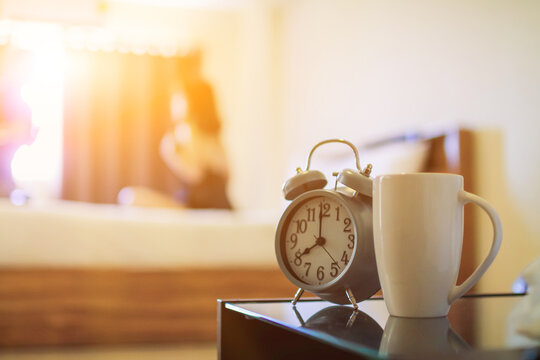 Soft light and Blurred image, alarm clock placed next to bed woke up at set time for woman to wake up and prepare to leave for work on time. The idea of ​​setting an alarm using an alarm clock