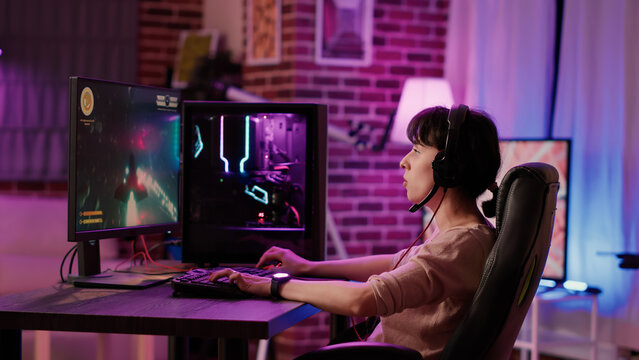 Caucasian gamer girl relaxing playing fast paced space shooter simulation on professional pc setup while talking using gaming headset. Woman streaming on internet rpg action game tournament gameplay.