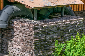 Exhaust ventilation pipes enclosed by a stone wall on a spring morning