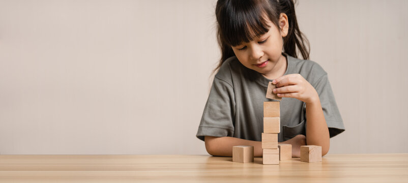 Girls build wooden cubes in layers with wooden blocks cube wooden box. girl playing with wooden block toys. Concept of early child development