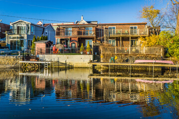 Fototapeta na wymiar View on the houses built near the Lachine canal in Montreal (Quebec, Canada) with their reflection in the calm waters on a clear fall day