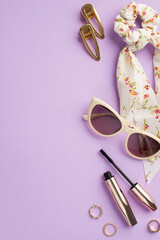 Make up concept. Top view vertical photo of white scarf scrunchy mascara sunglasses gold rings and two barrettes on isolated pastel violet background
